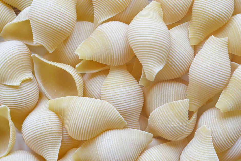 Various uncooked pasta shapes displayed together on white background`