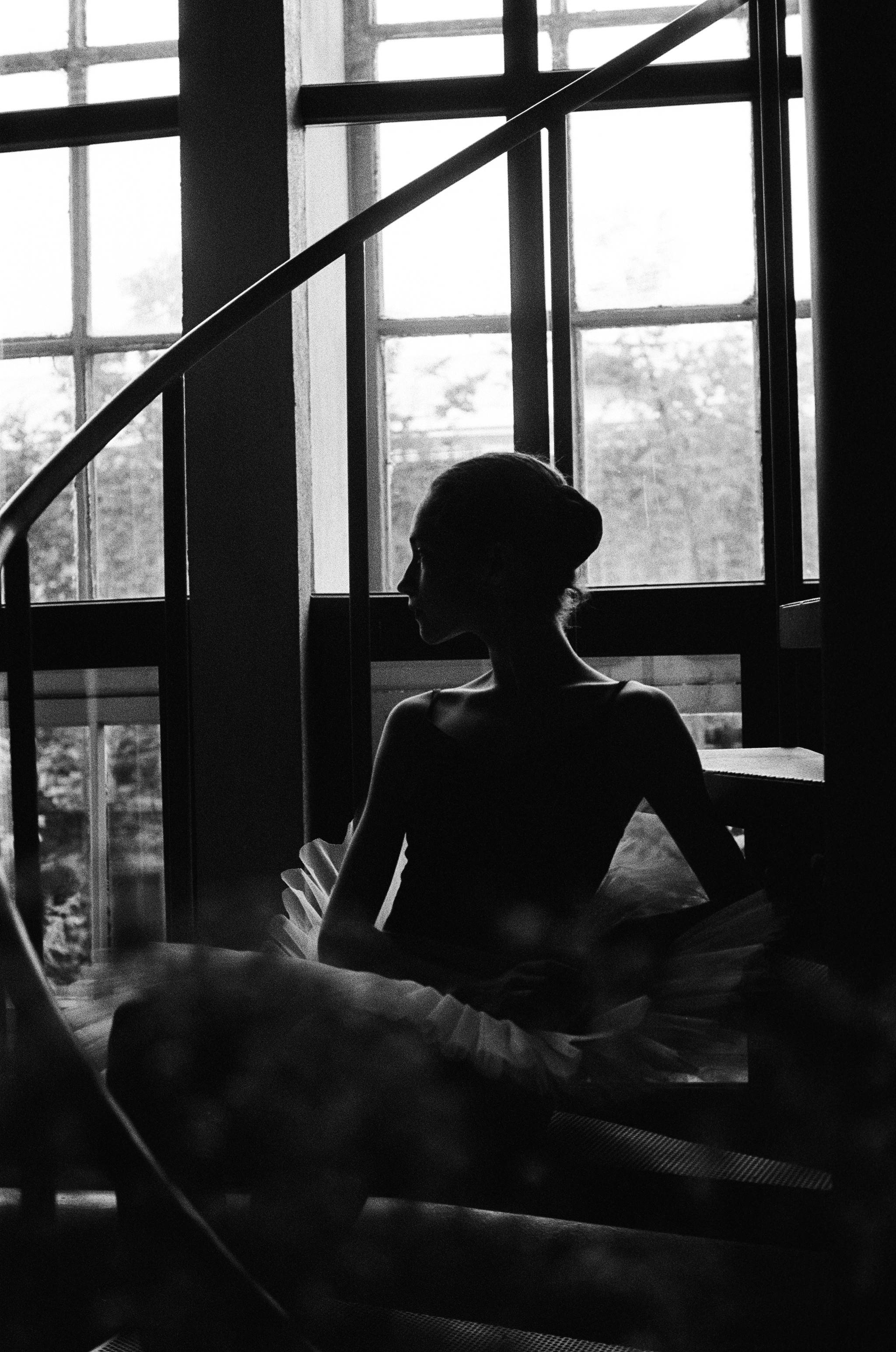 Graceful silhouette of a ballerina elegantly poised on a spiral staircase in black and white.