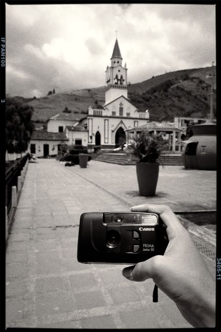 Analog camera held in front of a historic Colombian church in black and white.