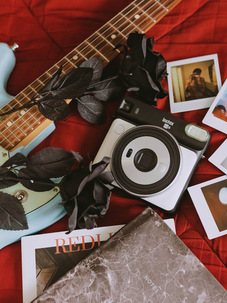 Instax Camera Beside Pictures And Artificial Flowers