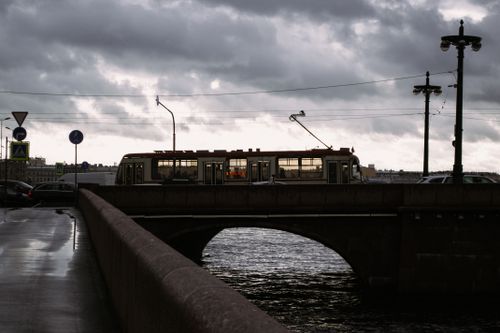 Free Tram crossing a bridge in a city setting, showcasing urban transportation and architecture. Stock Photo