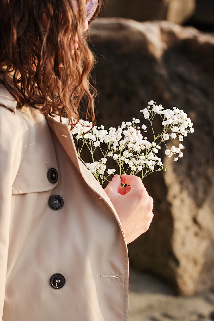 Person In Beige Coat Holding A Bunch Of  Baby's-Breath Flowers 