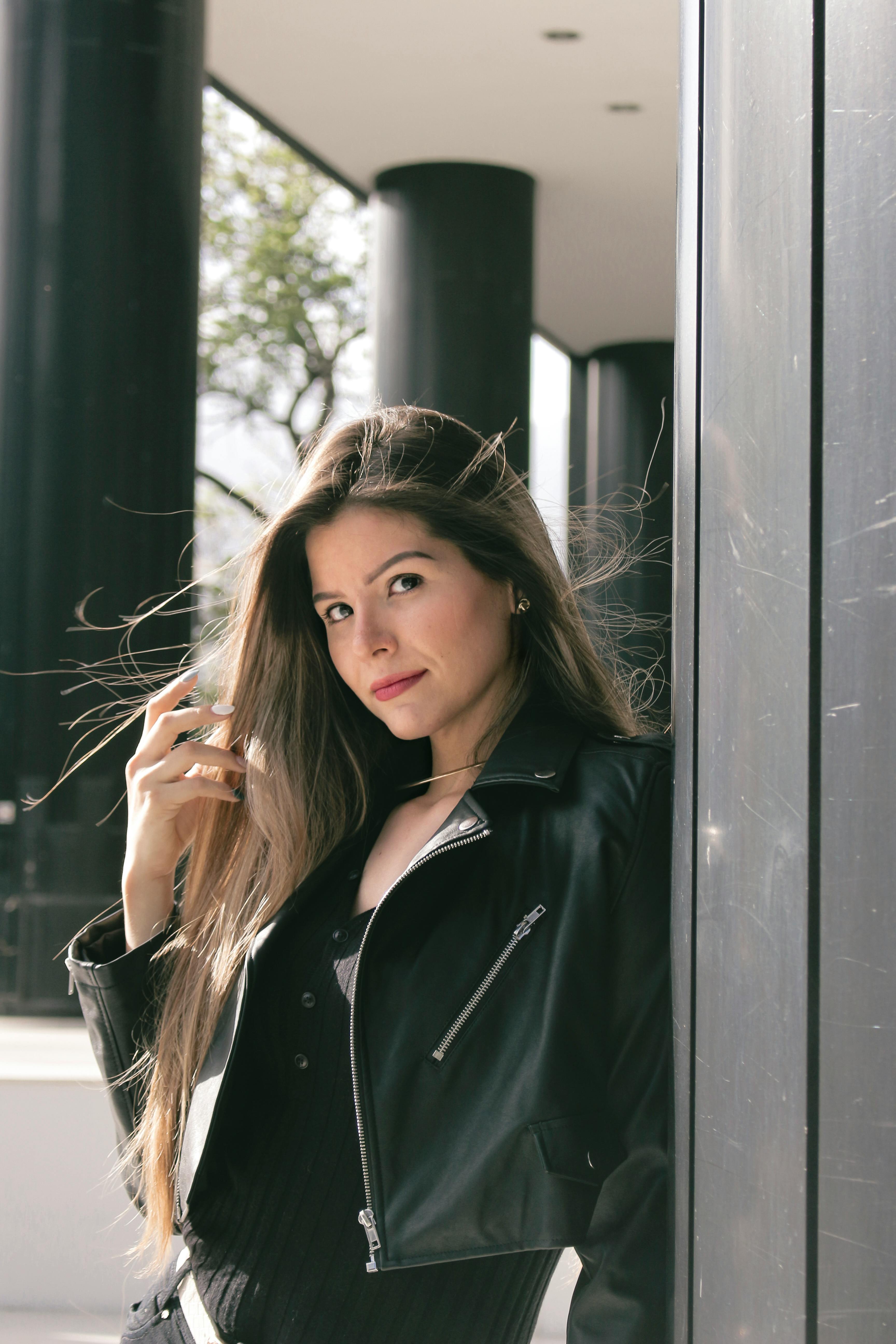 Free Stylish woman posing in a black leather jacket outdoors, exuding confidence and modern fashion. Stock Photo