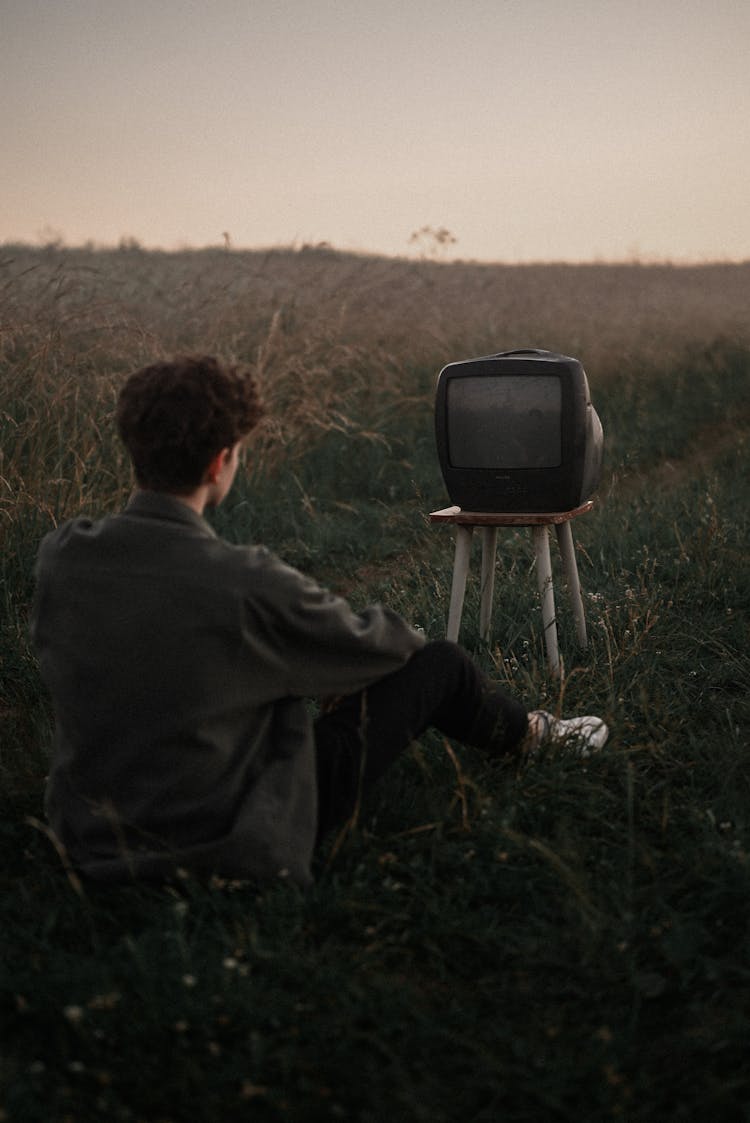 Man Sitting In Field, Watching TV