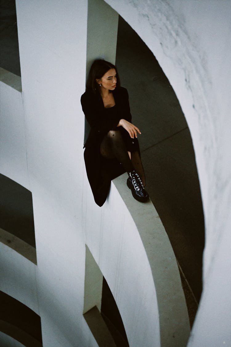 Woman Dressed In Black Sitting On Ledge