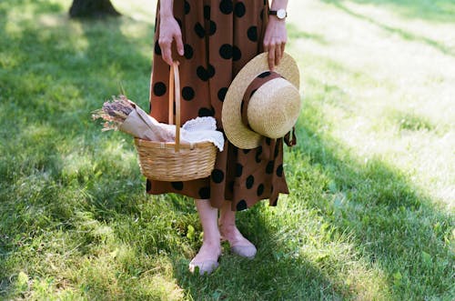 Woman Holding Hat and Basket with Flowers