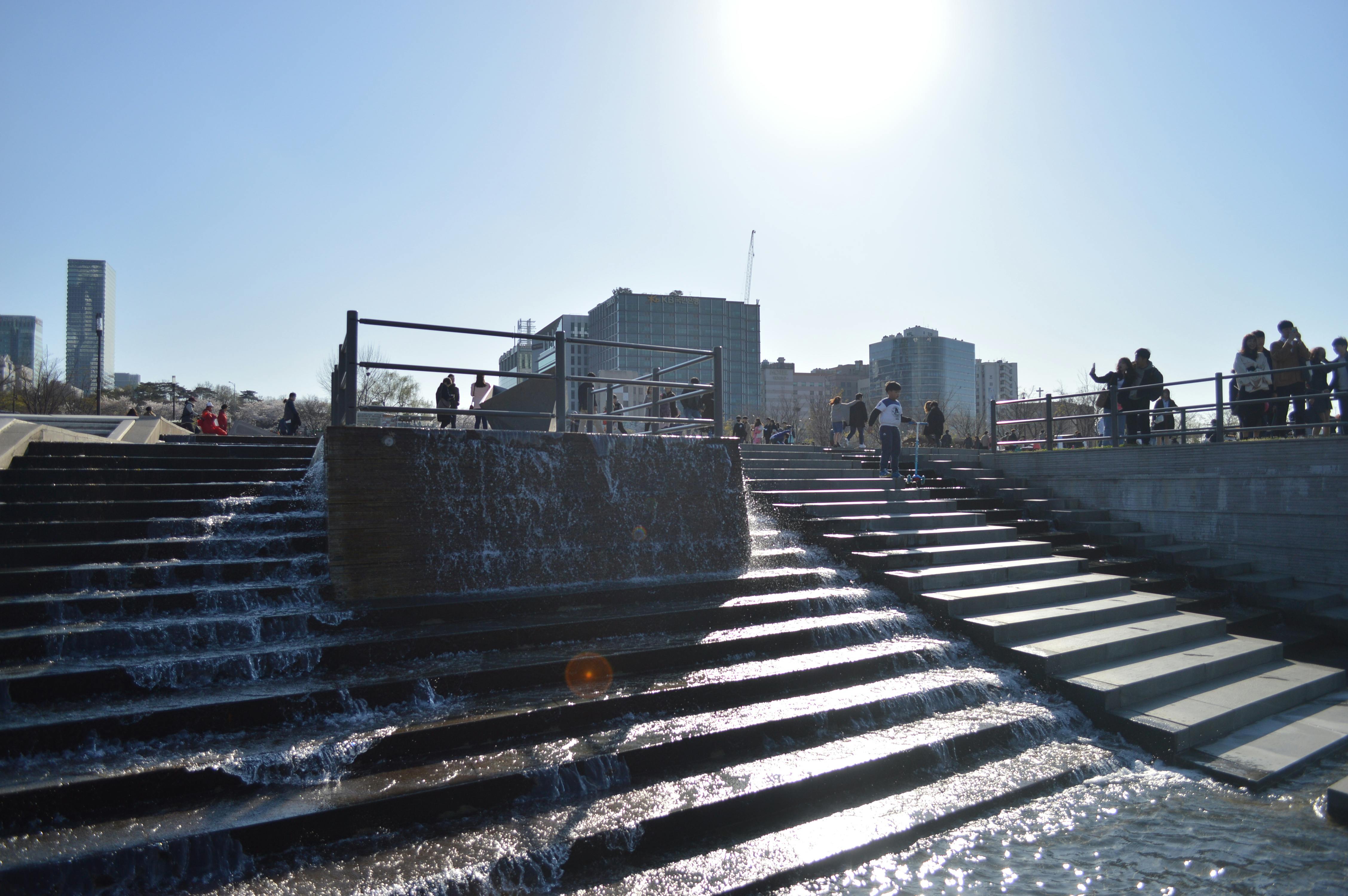 阳光明媚的城市中，人们沿着瀑布步道探索城市环境