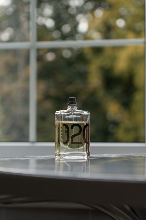 Free A stylish perfume bottle with modern design placed on a window sill with a blurred natural background. Stock Photo