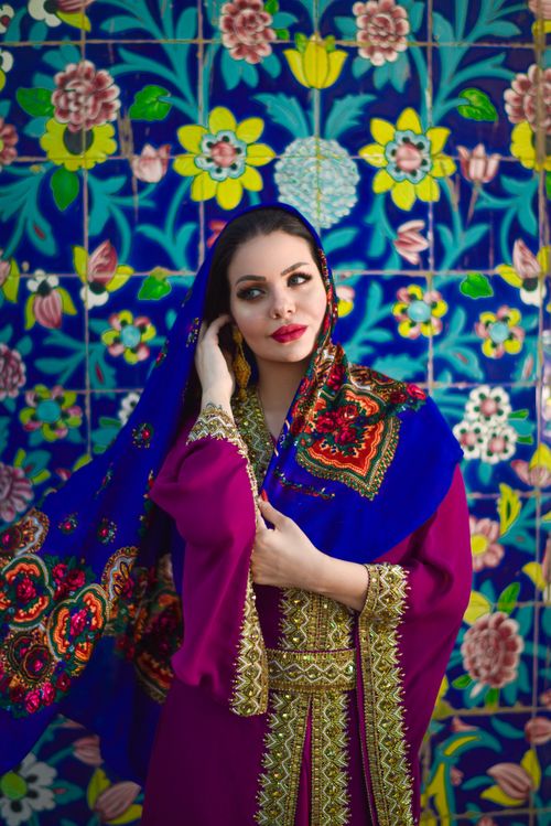Free Captivating portrait of a woman in traditional attire with a colorful floral backdrop in Baghdad. Stock Photo