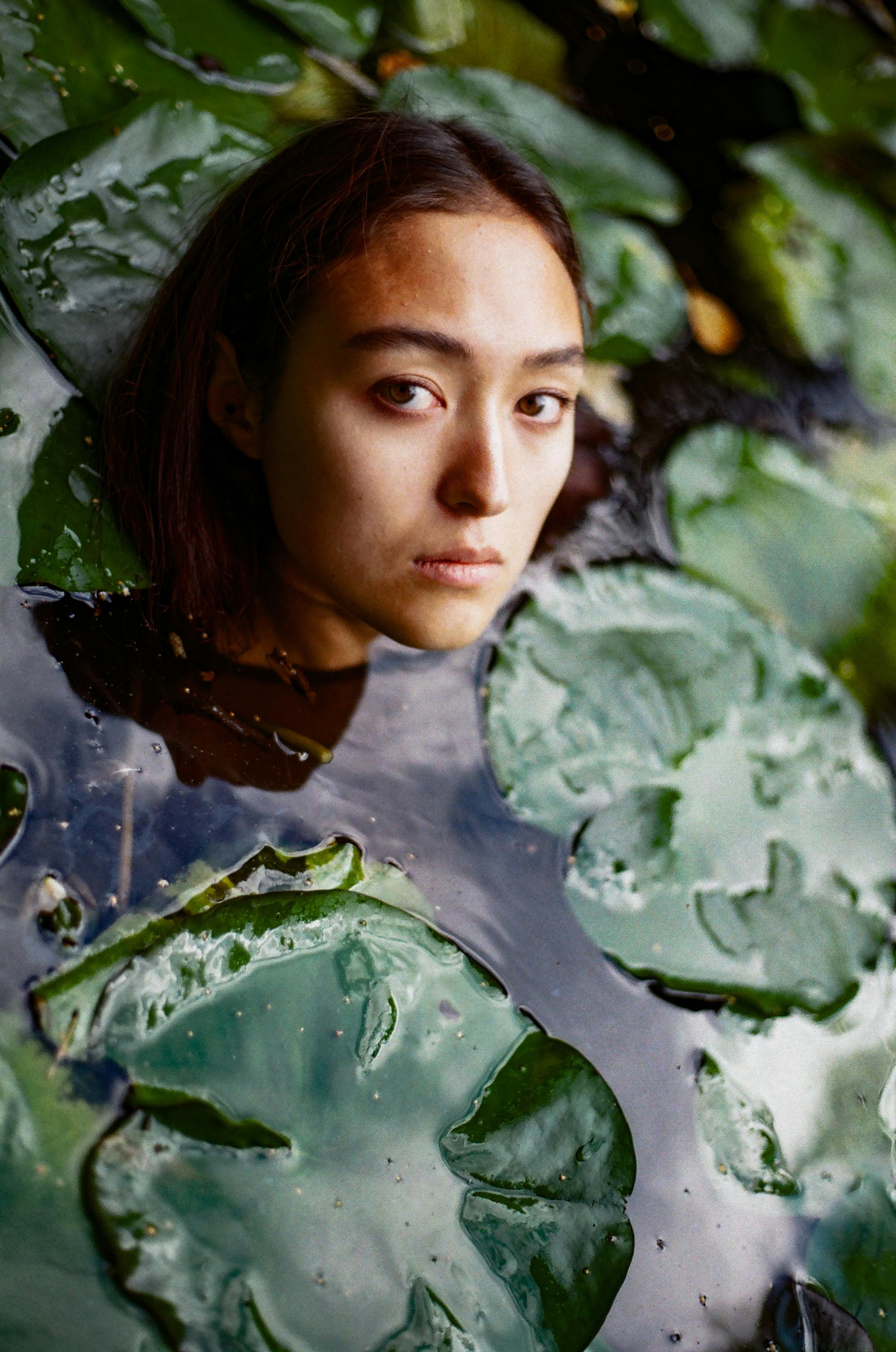 A captivating portrait of a woman surrounded by water lilies in a serene lotus pond, creating a tranquil atmosphere.