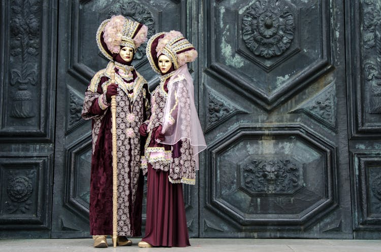 Man And Woman In Costumes In Front Of An Ornate Door