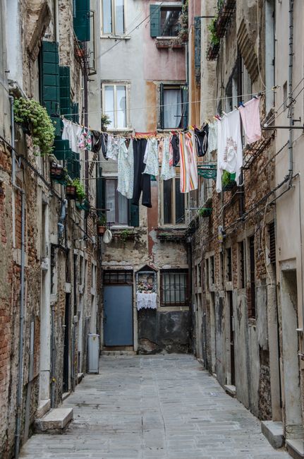 A narrow city alley with hanging laundry and rustic building facades showcasing urban decay.
