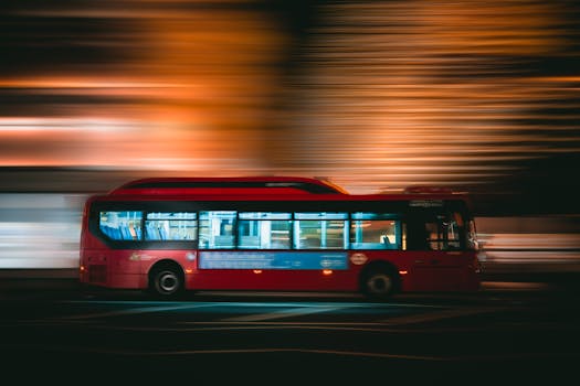 A dynamic shot of a red bus traveling at high speed, captured with motion blur at night.