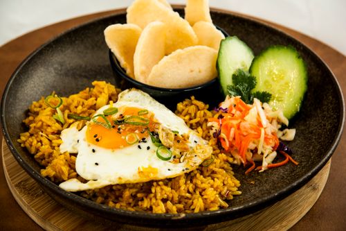 Free Close-up of a plate with fried rice, egg, and fresh vegetables garnished with sesame seeds. Stock Photo