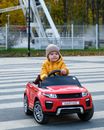 Child in Black Long Sleeve Shirt and Yellow Knit Cap Riding Red Ride on Toy Car