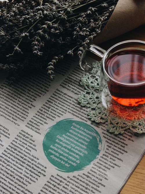 Free A warm tea setup with a glass cup, newspaper, and lavender bouquet creating a cozy vibe. Stock Photo