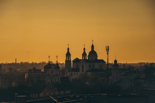 在橙色的日落天空下，大教堂的轮廓与塔和圆顶清晰可见