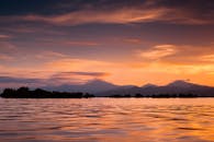 宁静的日落下，平静的湖水倒映着山脉，营造出静谧的氛围