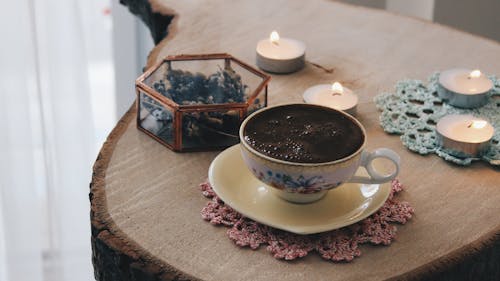 A Cup of Coffee on a Table with Lighted Candles