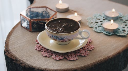 A Cup of Coffee on a Table with Lighted Candles