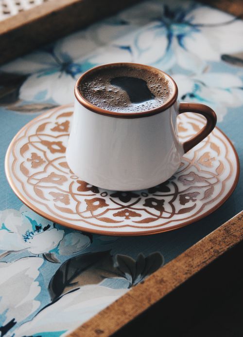Free Close-up of a decorated coffee cup on a floral-patterned tray, indoors. Stock Photo