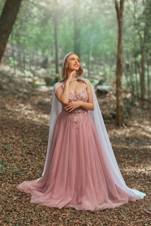 Blond Woman in Princess Gown Standing in Middle of Forest