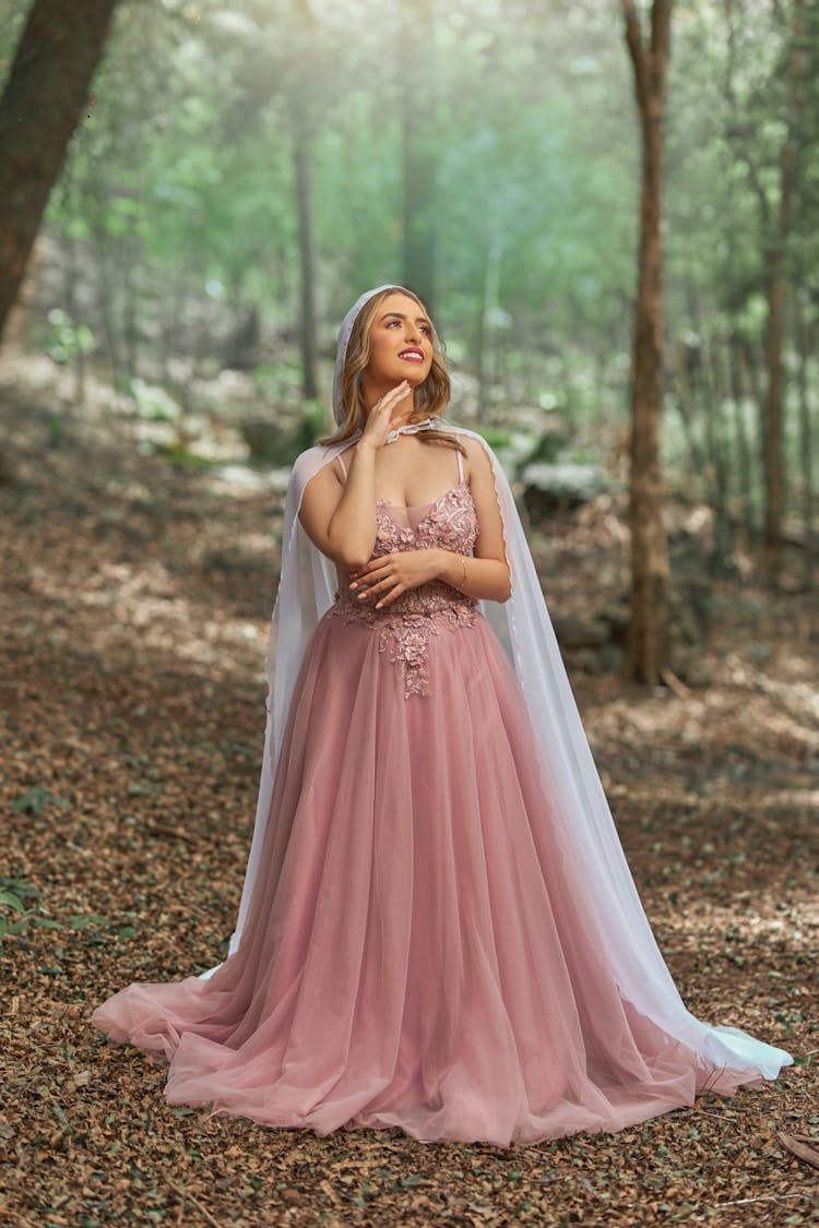 Blond Woman In Princess Gown Standing In Middle Of Forest