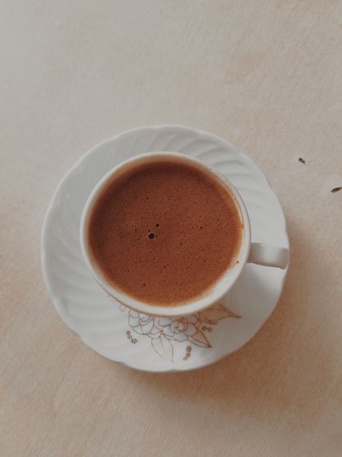 Free Top view of a simple coffee cup and saucer with brown beverage on a beige background. Stock Photo