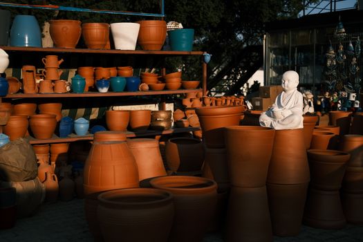 A collection of clay pots and sculptures in warm lighting on wooden shelves, showcasing handmade art.