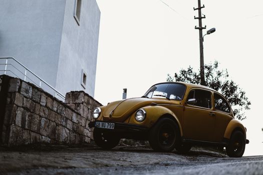 A classic yellow Volkswagen Beetle parked on a slope, showcasing vintage charm.