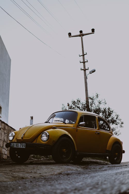 Yellow Volkswagen Beetle Parked Beside Gray Concrete Building