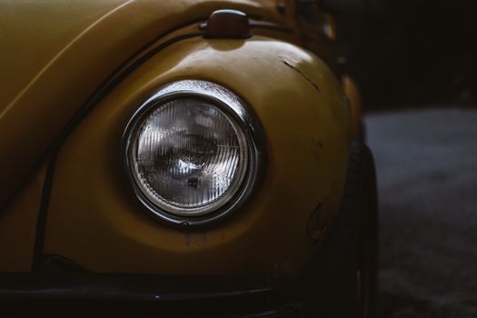 A detailed close-up of a vintage yellow Volkswagen Beetle headlight, showcasing its classic design.