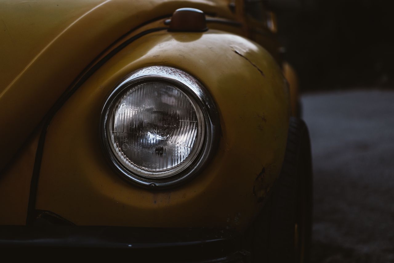 a detailed close up of a vintage yellow volkswagen beetle headlight sh