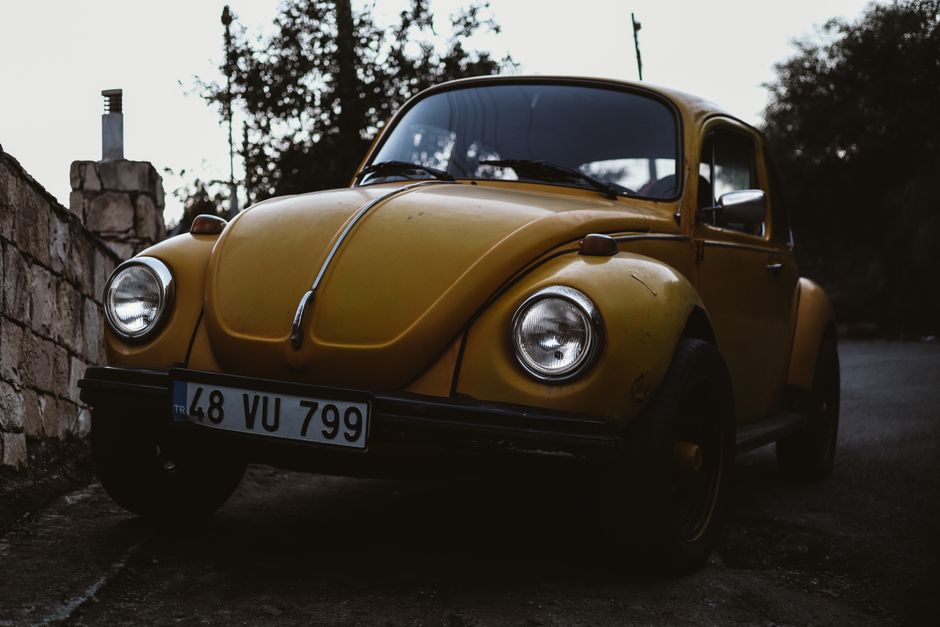 Classic yellow Volkswagen Beetle car photographed in an outdoor setting, showcasing vintage charm.