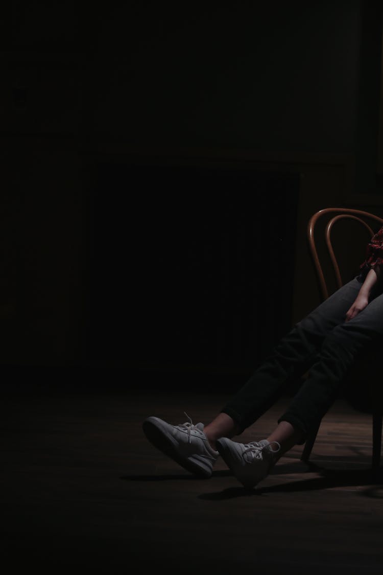 A Person Sitting On A Chair Inside A Dark Room