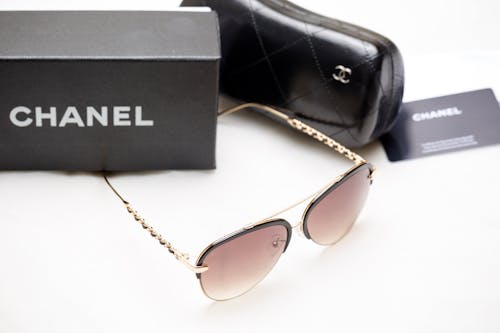Gold Framed Sunglasses Beside a Case and Box