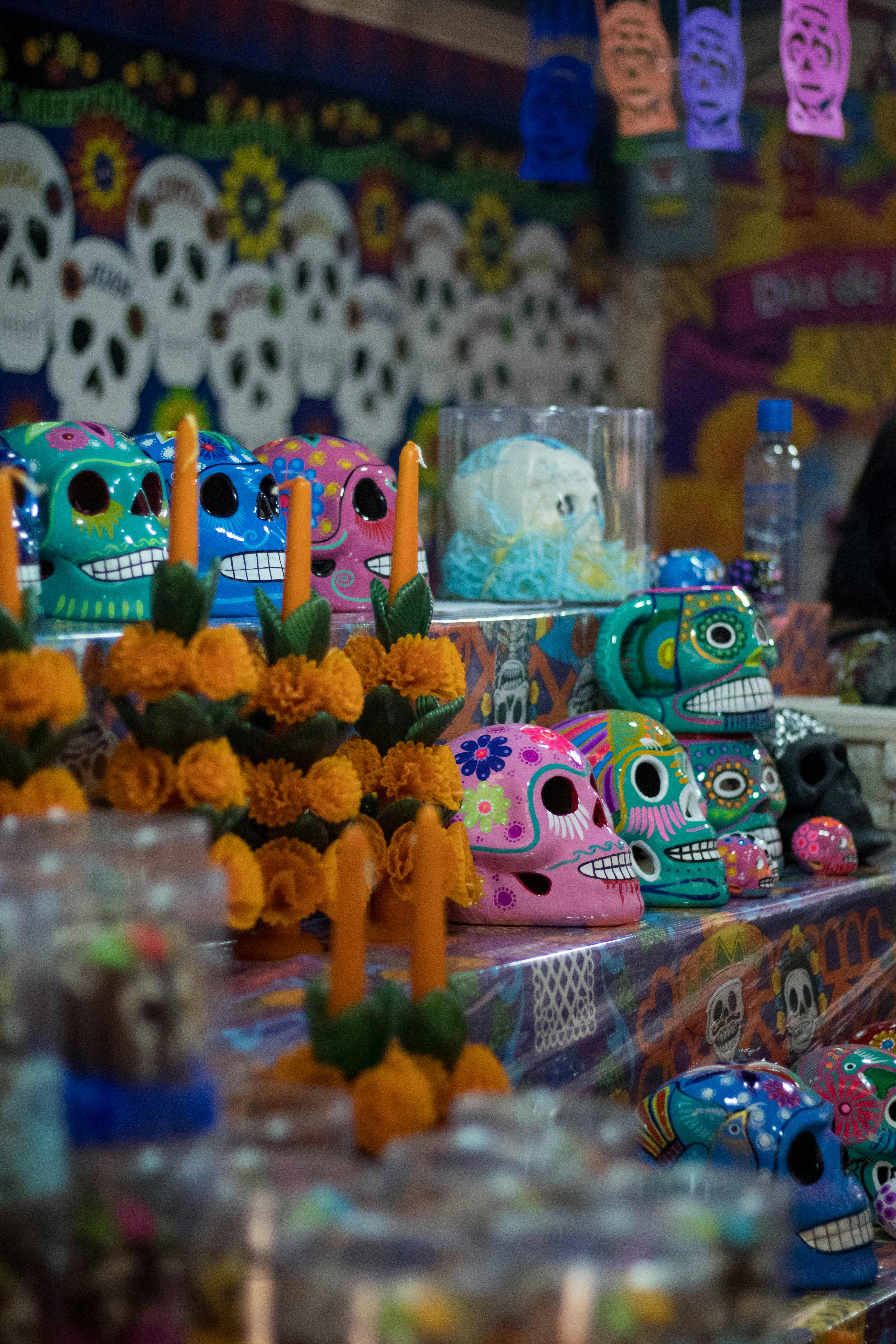 Vibrant display of Day of the Dead skulls and floral arrangements in a Mexican souvenir store.