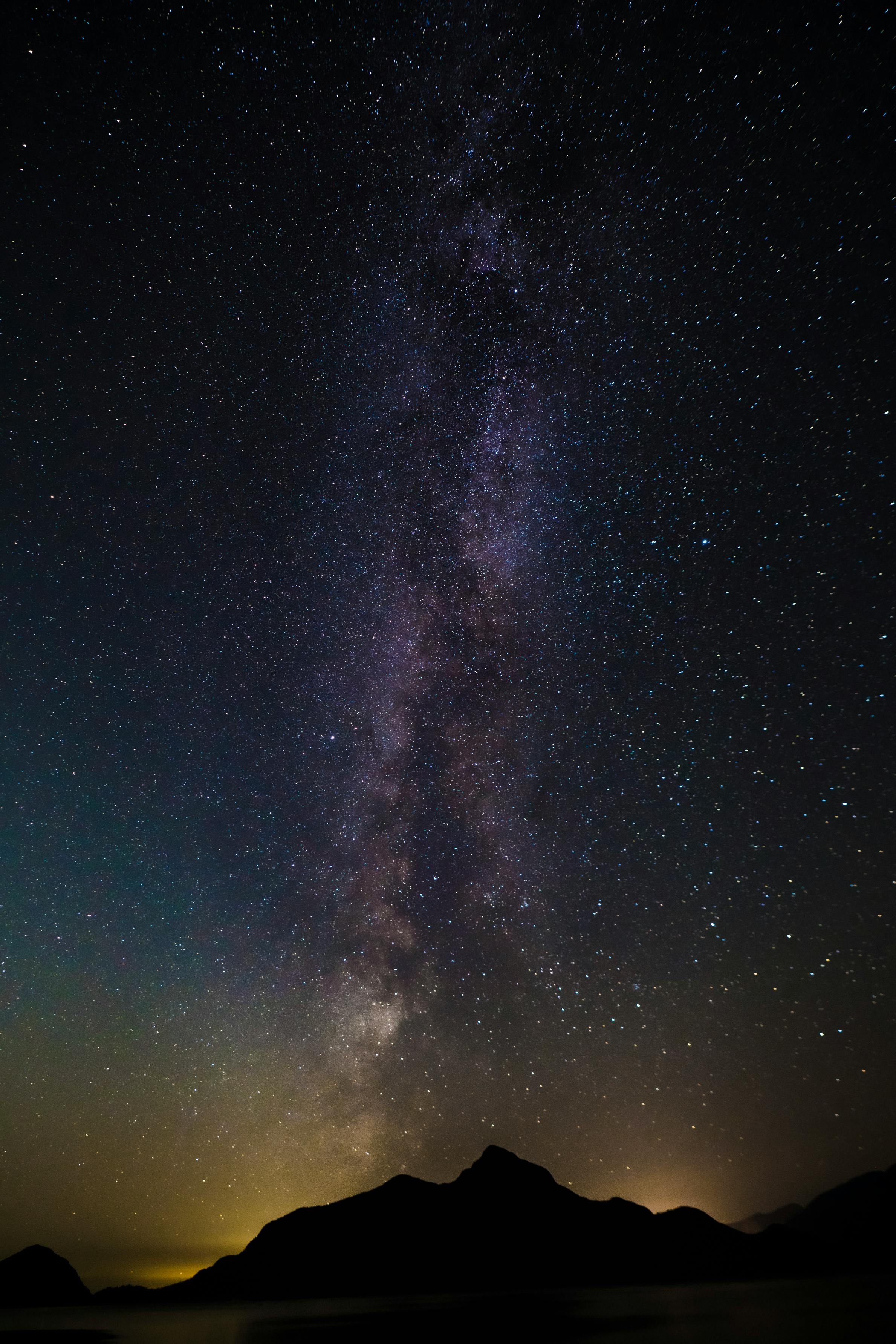 Breathtaking view of the Milky Way galaxy over a silhouette of a mountain range at night.
