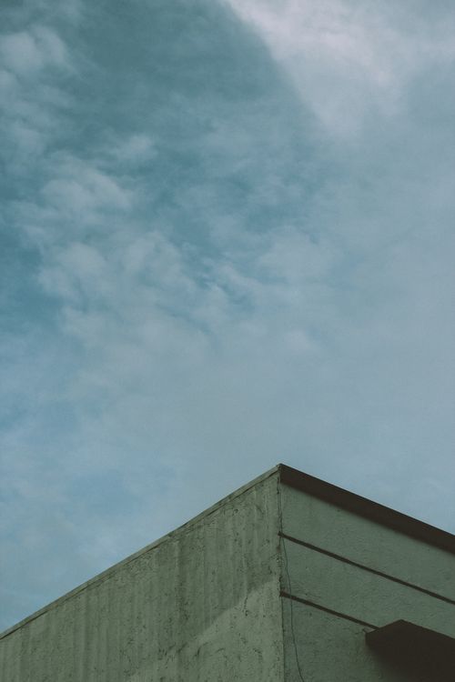Free Concrete building corner with blue sky and clouds, ideal for backgrounds. Stock Photo