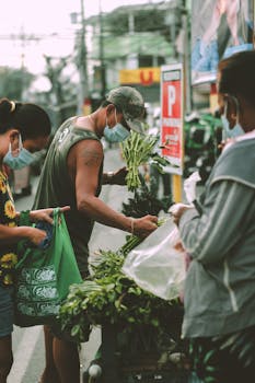 People buying fresh vegetables at an outdoor market in Imus, Philippines.