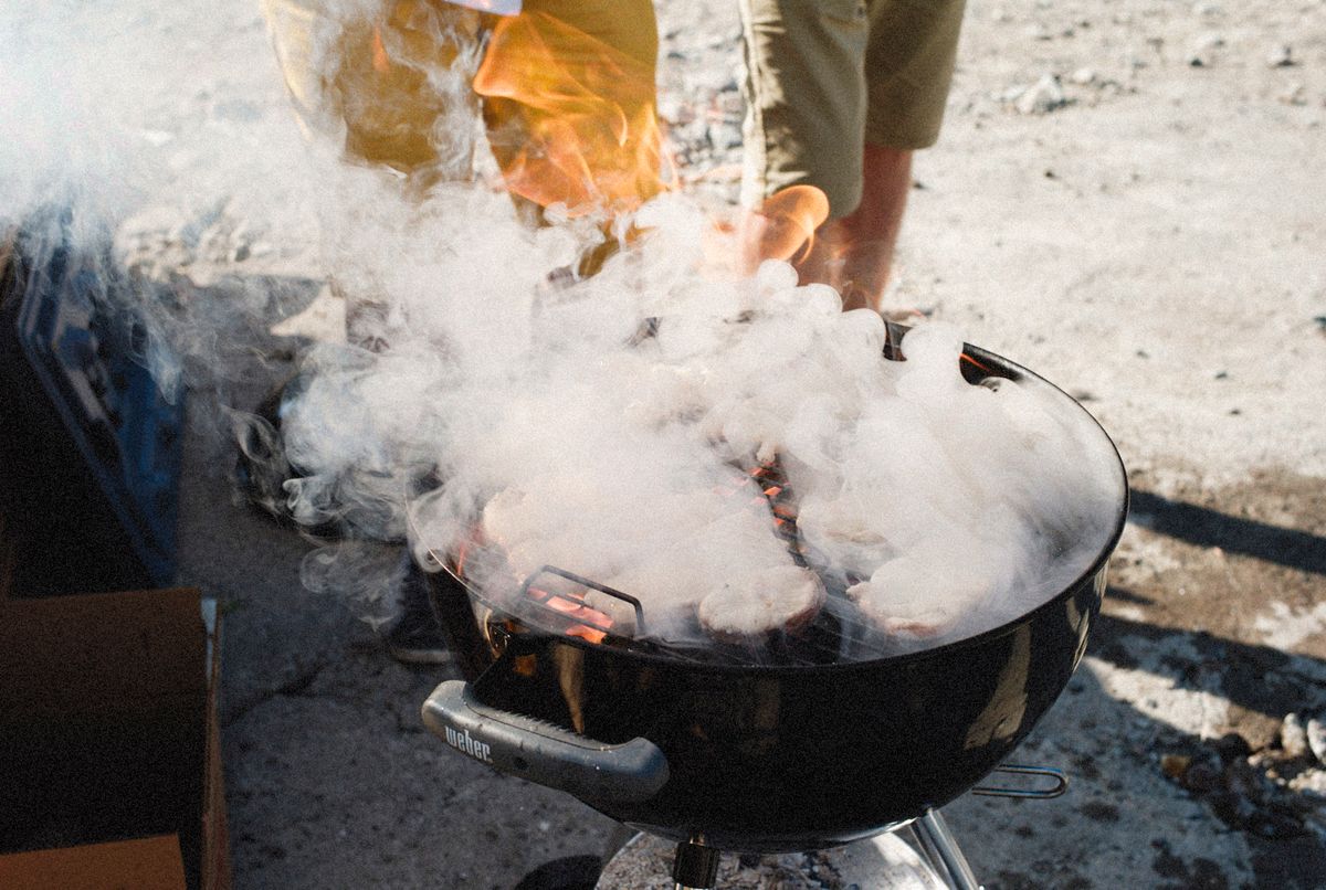 Plumes of aromatic wood smoke rising from a classic outdoor cookout grill