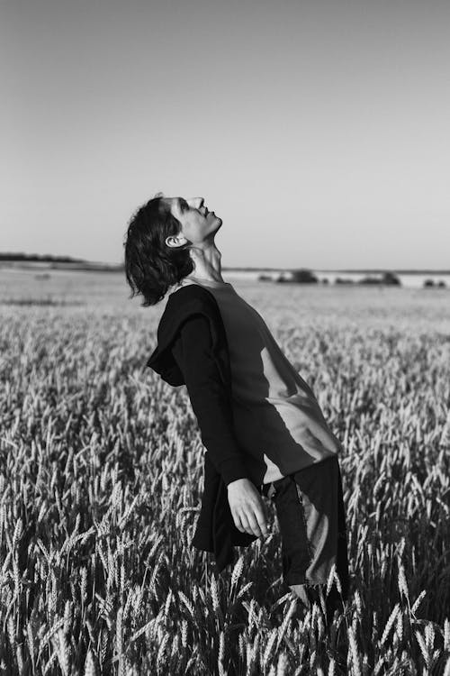 Grayscale Photo of a Man in a Wheat Field Looking Up