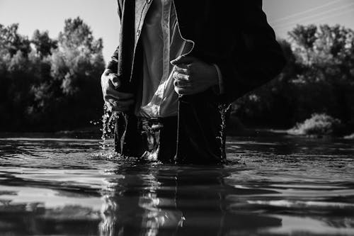 Grayscale Photo of Person Standing on the Lake 