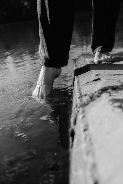 Free A Person's Foot Touching Water Stock Photo