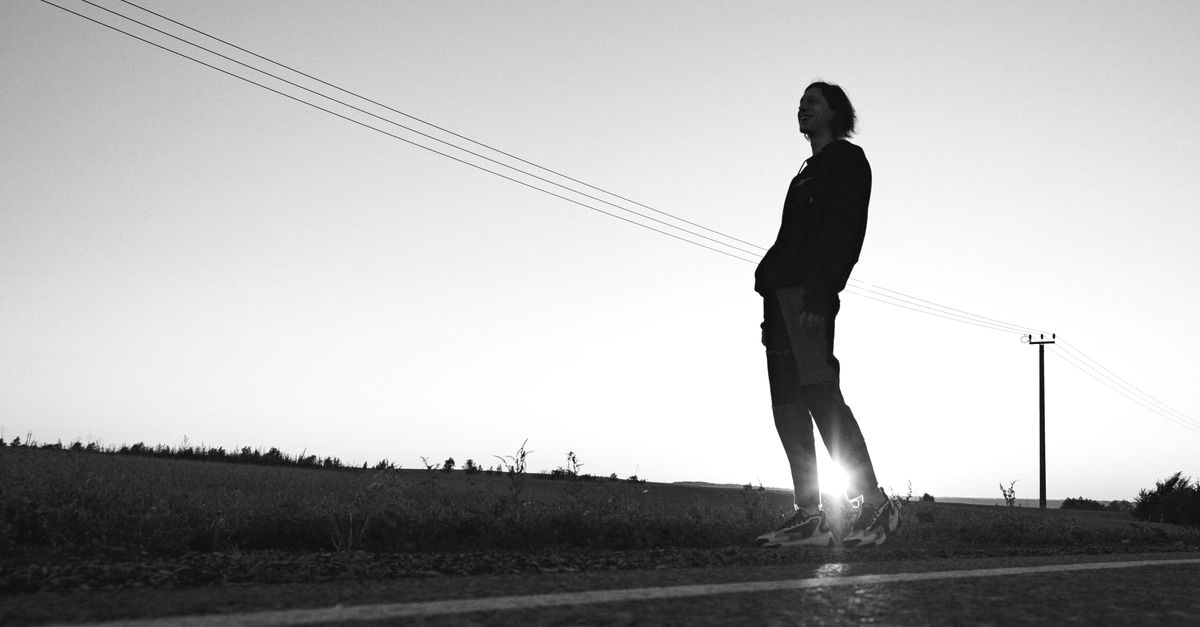 Person standing at a fork in the road at sunset