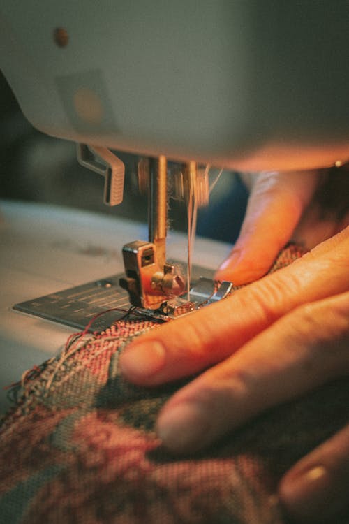 Person Sewing Green and Red Textile