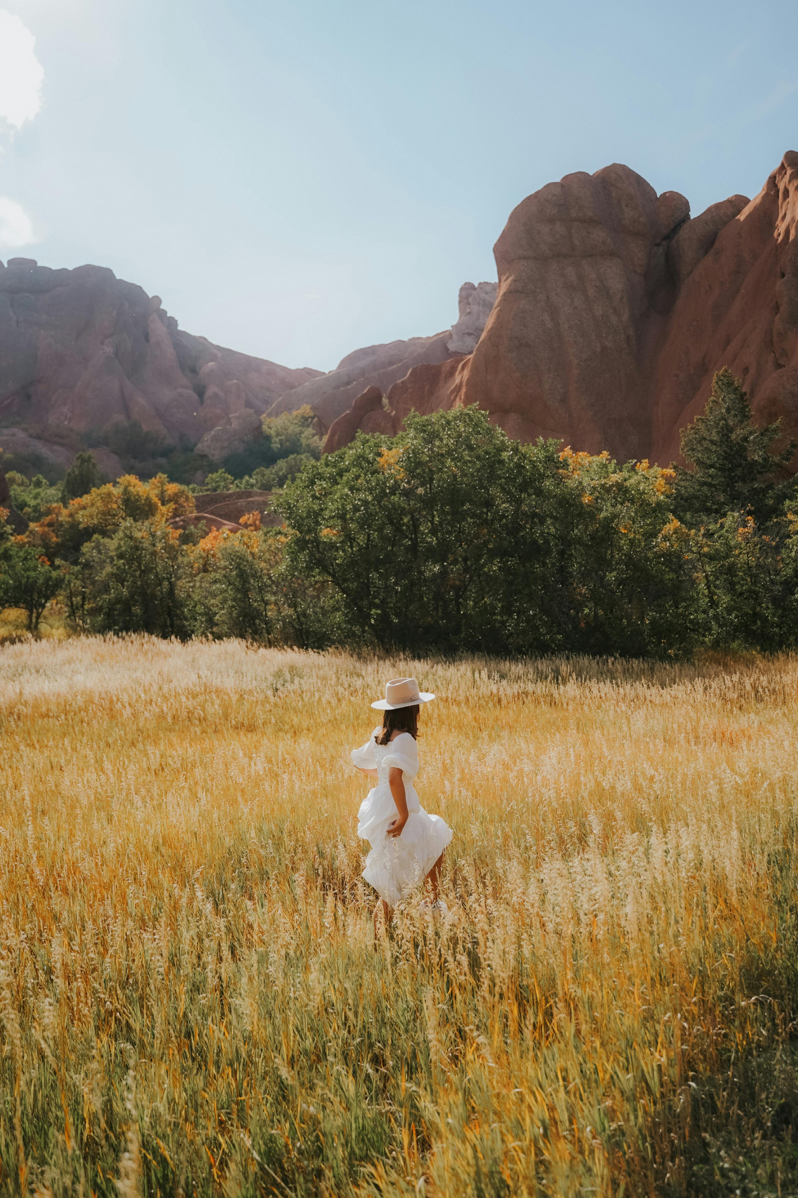 woman in white dress walking through field