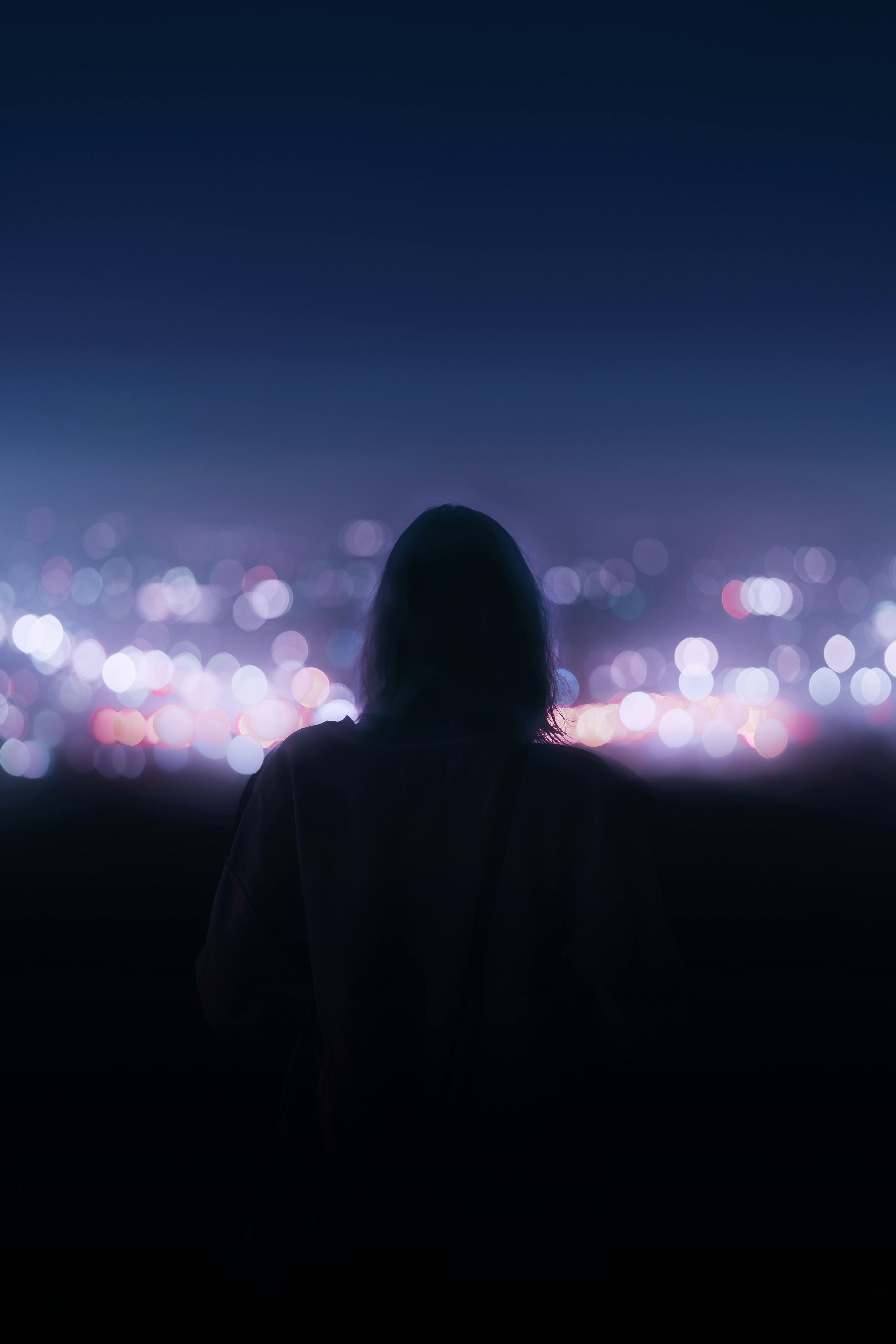 Silhouette of a person gazing at the vibrant nighttime cityscape of Los Angeles.
