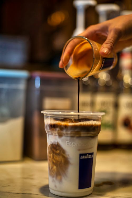 Free A Hand Pouring Chocolate Syrup on the Cup of Coffee Stock Photo