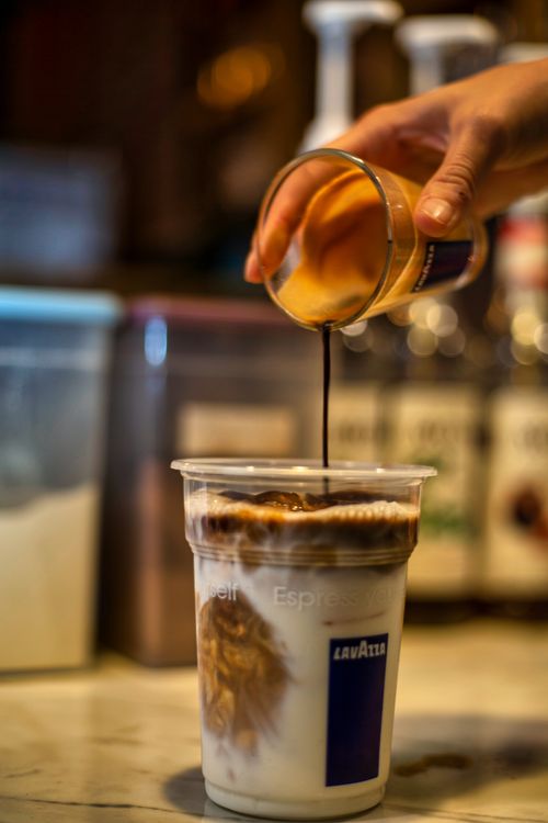 Free Close-up of Lavazza espresso being poured into a cup, creating beautiful swirls. Stock Photo